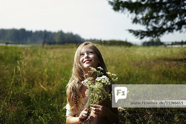 Kaukasisches Mädchen hält einen Strauß Wildblumen im Feld