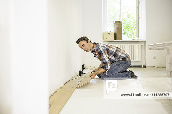 Man laying parquet in apartment