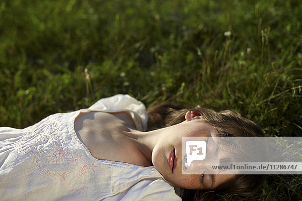 Kaukasisches Mädchen liegt mit geschlossenen Augen im Gras