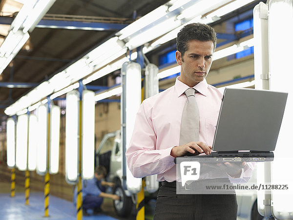 Mann mit Laptop in einem Automobilwerk