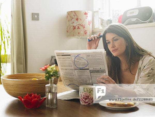 Portrait of Woman Looking Through Newspaper Classifieds