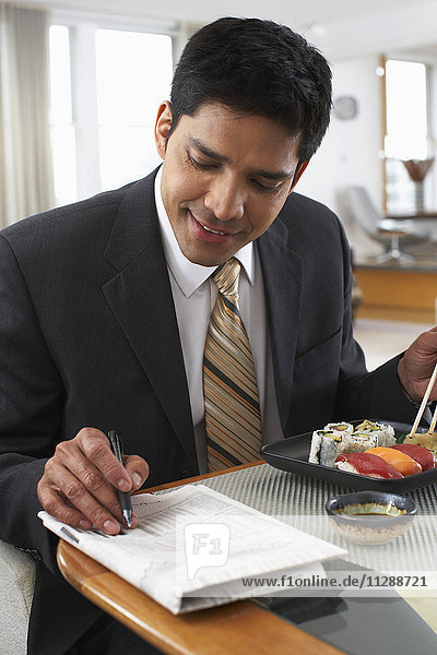 Mann mit Zeitung und Sushi