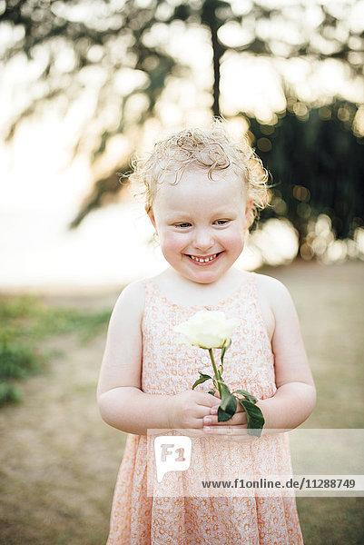 Porträt eines lächelnden Mädchens mit weißer Rose