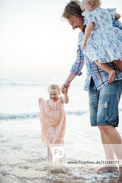 Vater mit Töchtern am Strand