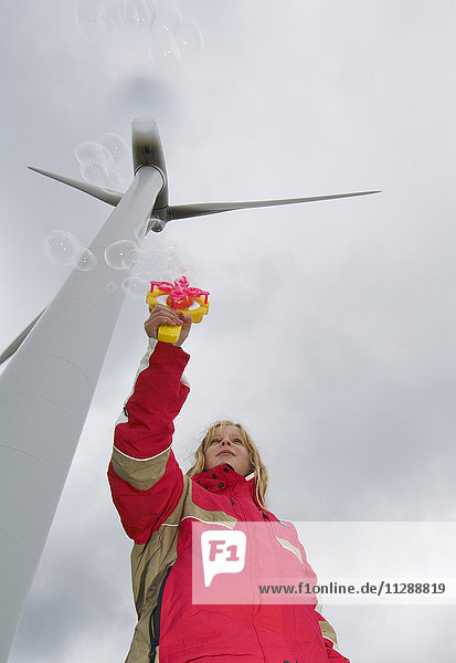Mädchen bläst Seifenblasen an einer Windturbine  Dänemark