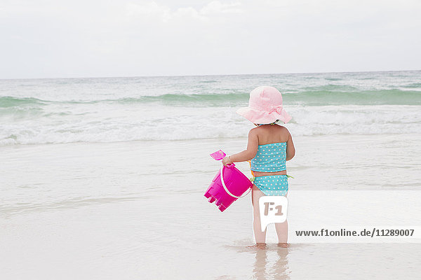 Toddler Girl Playing in Ocean with Shovel and Bucket at Beach  Destin  Florida  USA
