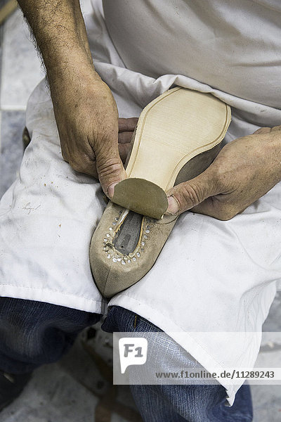 Schuhmacher beim Aufsetzen der Sohle auf einen Schuh in seiner Werkstatt