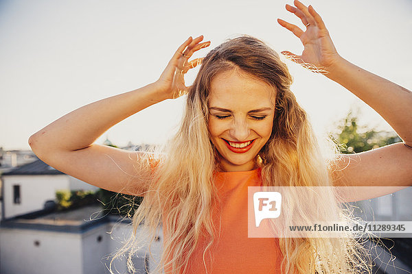 Smiling blond woman dancing on rooftop terrace