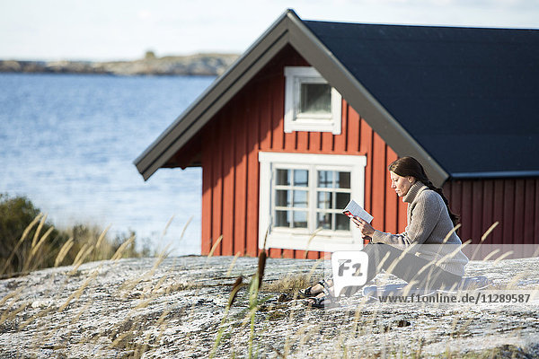 Frau liest Buch an der Küste