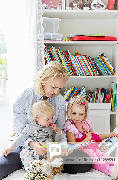 Mutter liest ihren Töchtern ein Buch vor