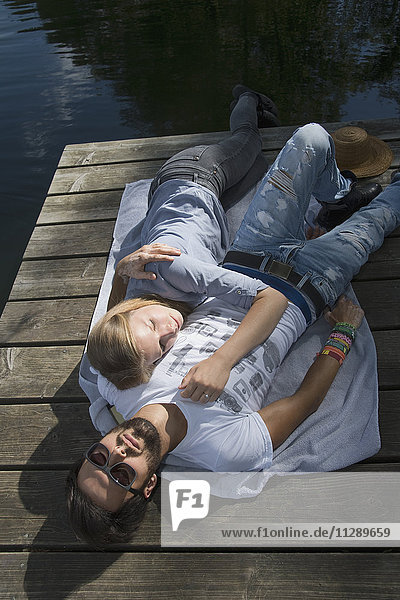 Entspanntes junges Paar auf einem Steg am See liegend