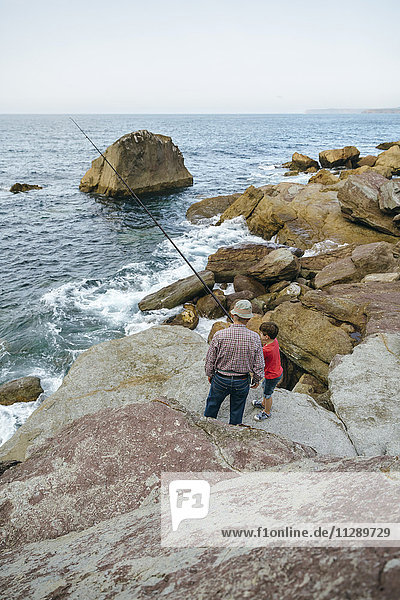 Großvater und Enkel beim gemeinsamen Fischen am Meer