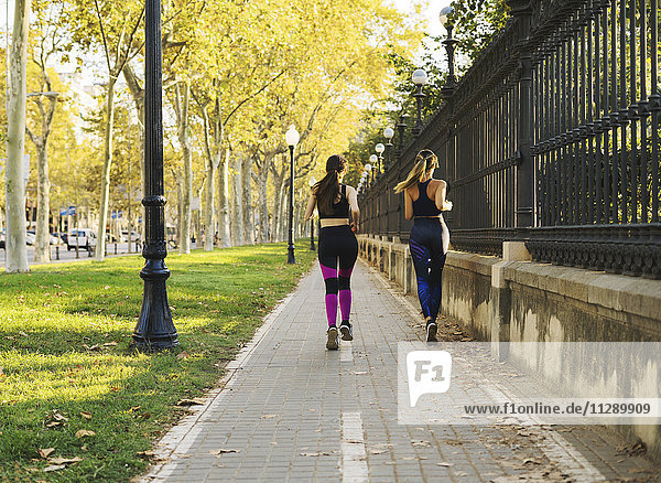 Zwei junge Frauen joggen auf dem Bürgersteig