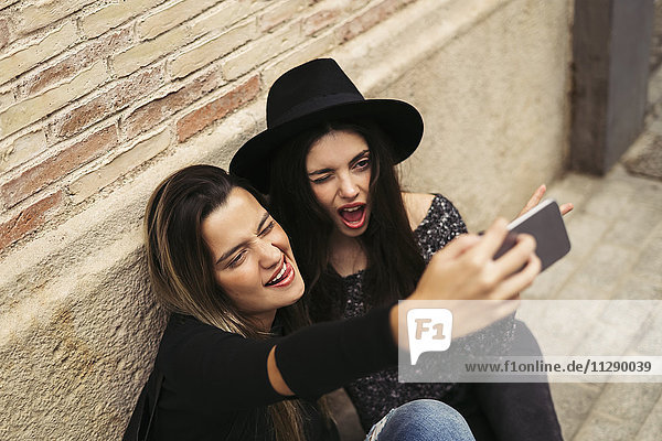 Zwei beste Freunde  die lustige Gesichter ziehen  während sie Selfie mit dem Handy nehmen.
