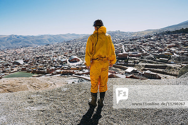 Bolivia  Potosi  back view of tourist wearing protective clothing looking to the city
