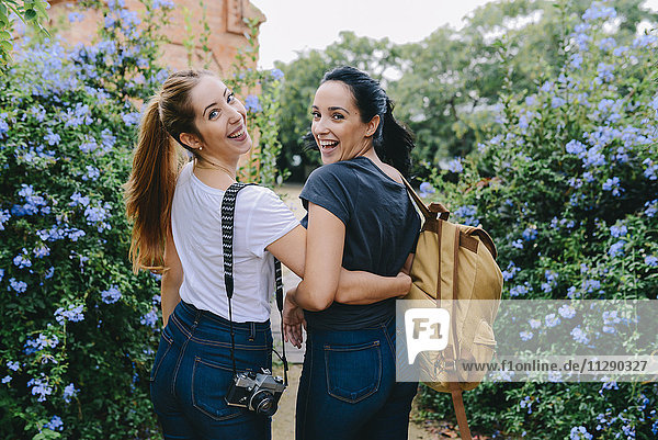 Zwei glückliche junge Frauen mit Kamera und Rucksack