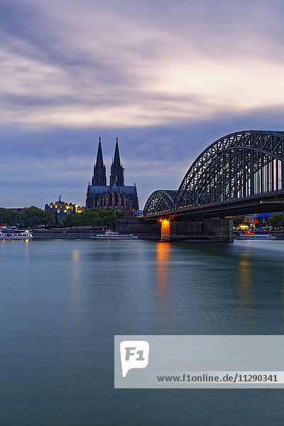 Deutschland,  Köln,  Blick auf den Kölner Dom mit Hohenzollernbrücke im Vordergrund bei Abenddämmerung