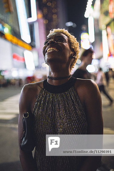 USA  New York City  lächelnde junge Frau am Times Square bei Nacht aufblickend