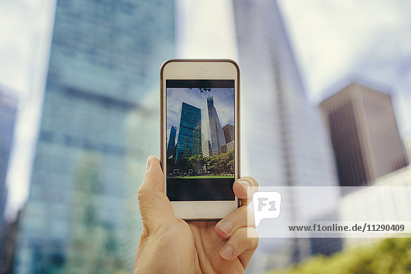 Mann fotografiert mit Handy in Manhattan