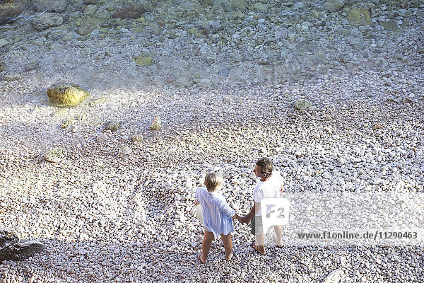 Draufsicht des Seniorenpaares  das Hand in Hand am Strand steht.