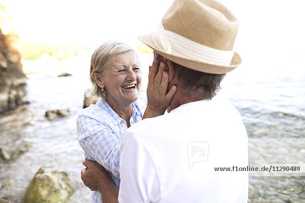 Lachende Frau von Angesicht zu Angesicht mit ihrem Mann vor dem Meer.