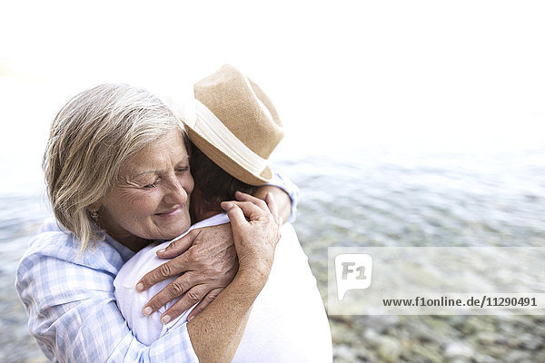 Glückliches Seniorenpaar umarmt sich vor dem Meer