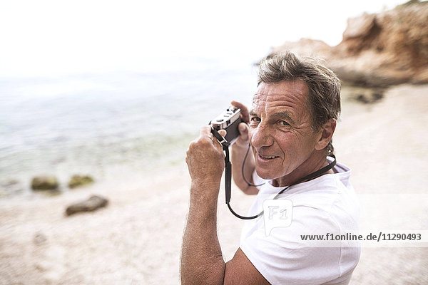 Porträt eines älteren Mannes beim Fotografieren am Strand
