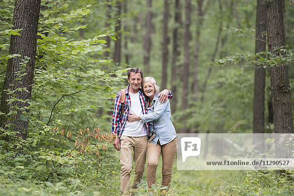 Ein glückliches älteres Paar  das im Wald spazieren geht.