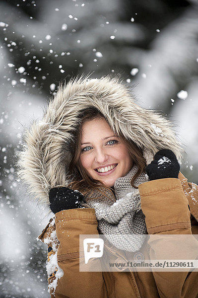 Junge Frau mit Fellkapuze im Schneefall  Portrait