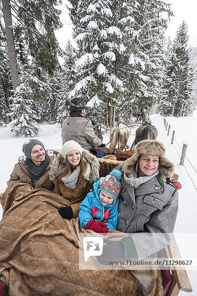 Familie genießt im Winter eine Fahrt mit dem Pferdeschlitten
