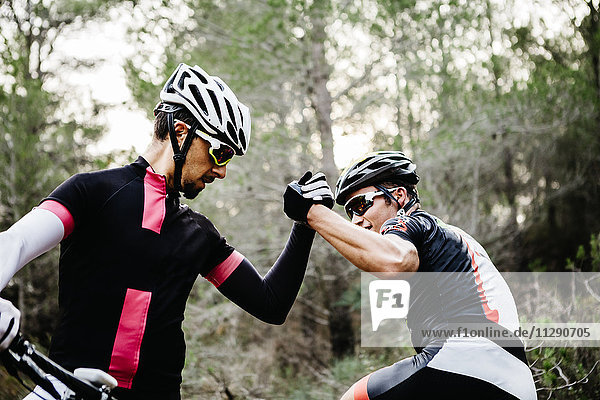Two mountainbikers shaking hands in forest