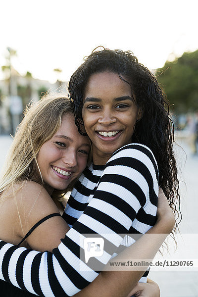 Zwei glückliche junge Frauen  die sich im Freien umarmen.