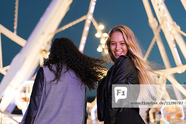 Zwei glückliche junge Frauen auf einem Jahrmarkt bei Nacht