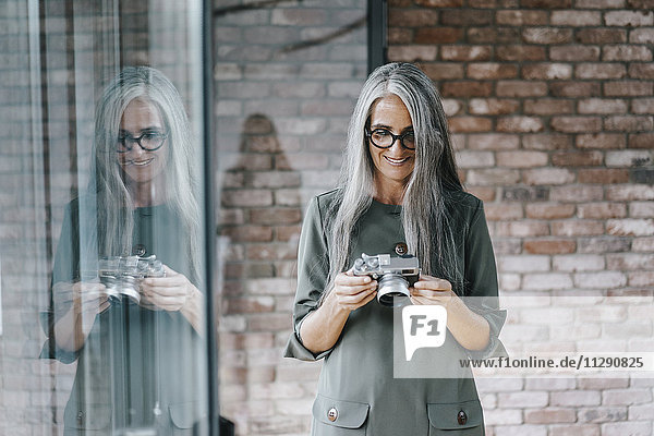 Smiling woman with long grey hair holding camera