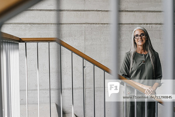 Portrait of smiling woman with long grey hair in staircase