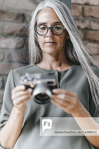 Woman with long grey hair holding camera