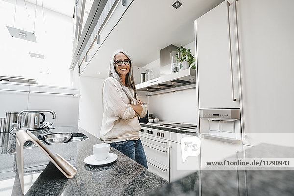 Lächelnde Frau mit langen grauen Haaren in der Küche