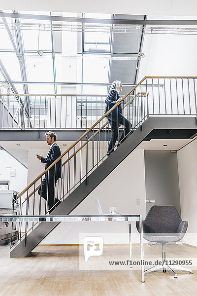 Businesswoman and businessman walking on stairs in a loft