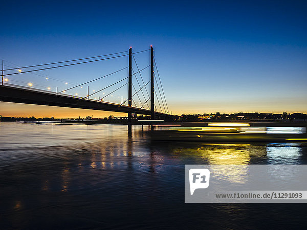 Deutschland  Düsseldorf  Blick auf Rheinknie-Brücke mit Rhein im Vordergrund zur goldenen Stunde