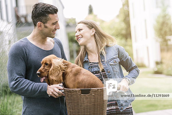 Smiling couple with dog in bicycle basket