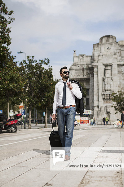 Businessman walking with suitcase in the city