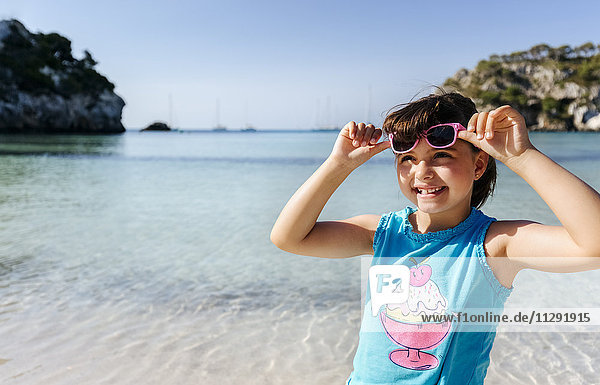 Porträt eines lächelnden kleinen Mädchens vor dem Meer stehend