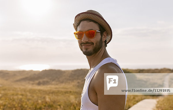 Smiling man wearing straw hat and orange sunglasses
