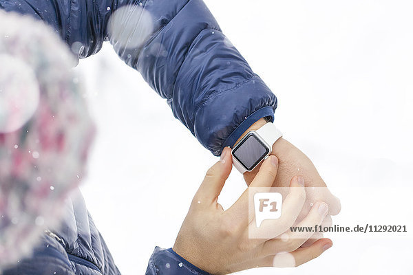 Man checking his smartwatch in winter  partial view
