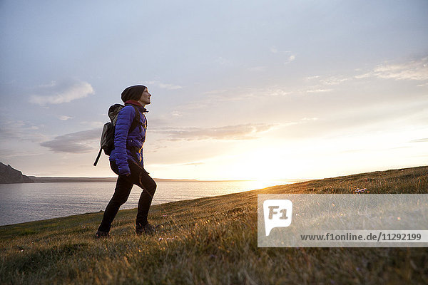 Island  Frau beim Wandern in der Dämmerung auf einem Hügel