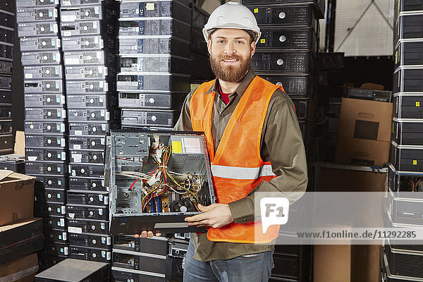 Worker in computer recycling plant holding pc casing