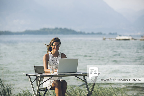 Italien  Gardasee  junge Frau am Tisch sitzend mit Laptop