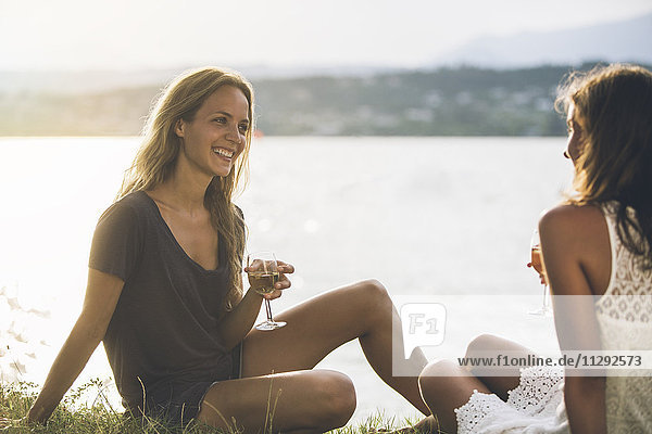 Italien  Gardasee  zwei junge Frauen am Seeufer bei einem Glas Wein