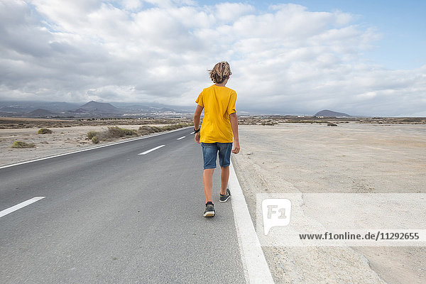 Spain  Tenerife  back view of boy walking on empty country road