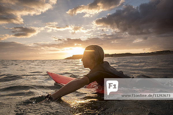 Spanien  Teneriffa  Junge beim Surfen im Meer bei Sonnenuntergang